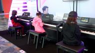 Music students practice their skills at a keyboard exhibit. (Photo by Jesse Grant/Getty Images for NAMM)